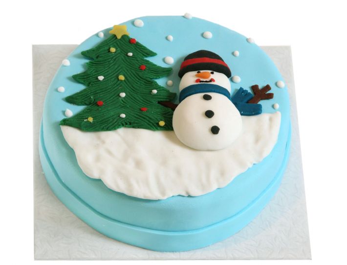 Winterliche Weihnachtstorte mit Schneemann, grünem Tannenbaum und Waldmotiv auf heller Oberfläche
