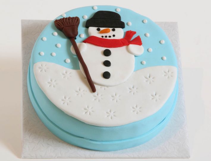 Schneemanntorte mit Schal, Besen und winterlicher Dekoration auf der Tortenoberfläche